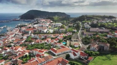 Tepedeki beyaz boyanmış binalar muhteşem bir sahile doğru sürünüyor.