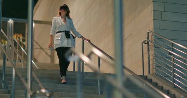 Stylish young woman walking down stairs. Model in trendy white and black outfit — Stock Video