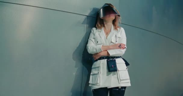 Стильная женщина в модной одежде позирует в синем свете на фоне стальной стены — стоковое видео