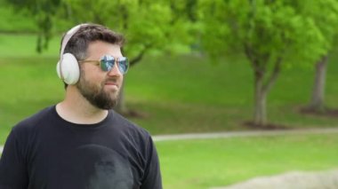 Kablosuz kulaklıkla müzik dinleyen gülümseyen sakallı adam. KIZIL HELİM