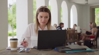 Serious successful woman connecting with colleagues by video conference call