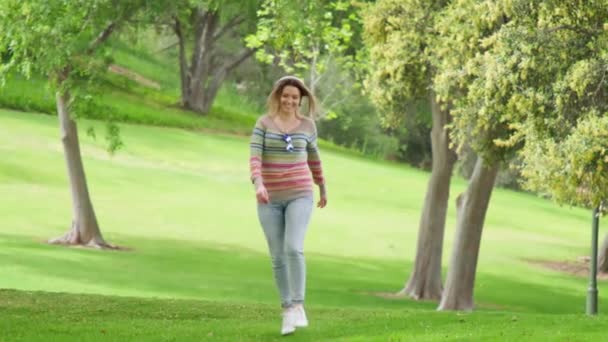 Gente en el parque verde en verano, feliz mujer sonriente saltando y escuchando música — Vídeo de stock