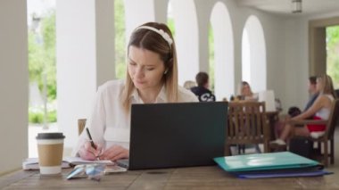 Beautiful young businesswoman wearing white shirt, using laptop sitting outside