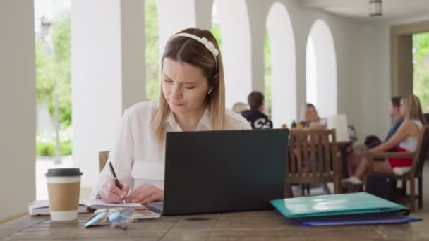 Beautiful young businesswoman wearing white shirt, using laptop sitting outside — Video Stock