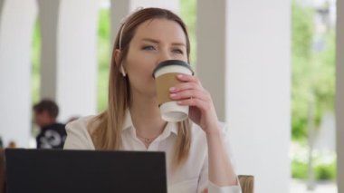 Concentrated young caucasian businesswoman drinking coffee outdoors, RED footage