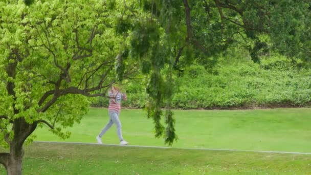 People in green park. Happy young woman walking in city urban park. RED footage — Vídeo de Stock