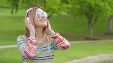 Positive woman or university student listening to music in wireless headphones