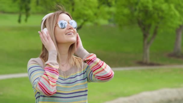 Positive woman or university student listening to music in wireless headphones — Αρχείο Βίντεο