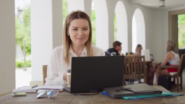 Joven mujer de negocios caucásica con auriculares comunicando vídeo por llamada — Vídeo de stock