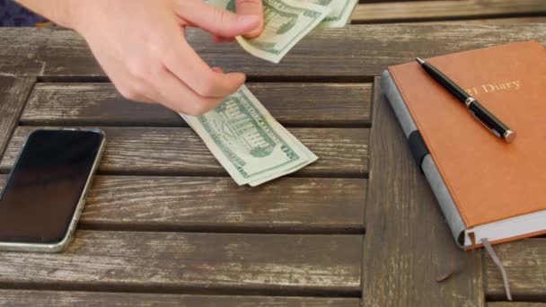 Человек считает банкноты на 20 долларов на деревянном столе, мировой экономический кризис — стоковое видео