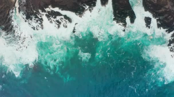 Вид с воздуха на голубоватые, пенные приливы, омывающие побережье — стоковое видео