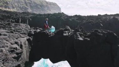 Bir kayaya tırmanan adam, Atlantik 'le yıkanmış.