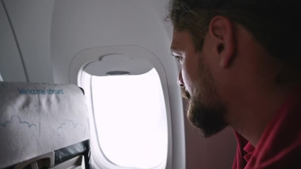 Widok z boku człowieka patrzącego przez okno samolotu — Wideo stockowe