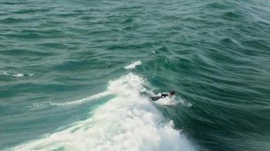 Sörfçü büyük yeşil okyanus dalgalarına biner. Kırmızı Helium Silah sinemasında çekildi.