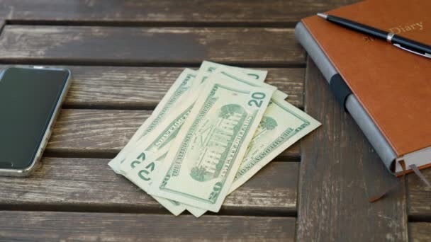 In Zeitlupe nimmt eine Frauenhand die 20-US-Dollar-Banknoten vom Holzdeck — Stockvideo