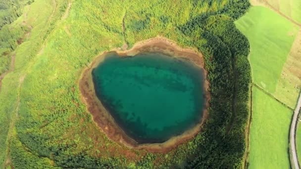 Imagens de drones sobre o lago esverdeado na cratera rodeado por uma paisagem vibrante — Vídeo de Stock