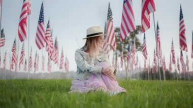 Ağır çekim vatansever kadın Amerikan bayraklarıyla gün batımını seyrediyor.