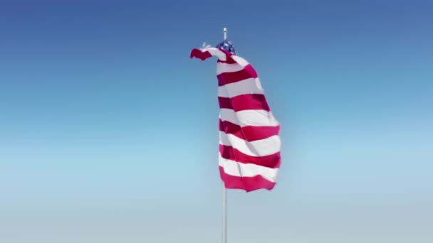 Fondo americano. Antena cinematográfica 4K de bandera estadounidense ondeando sobre cielo azul claro — Vídeo de stock