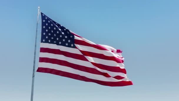 Prachtig filmisch uitzicht op zwaaiende Amerikaanse vlag, heldere blauwe lucht op de achtergrond — Stockvideo