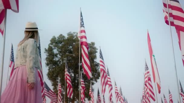 Cinematic slow motion of young stylish woman walking between many American flags — Stock video