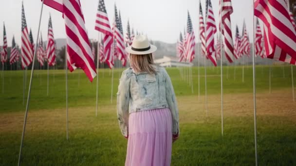 Gün batımında Amerikan bayraklarıyla güzel bir genç kadın. Bağımsızlık Günü 4K — Stok video