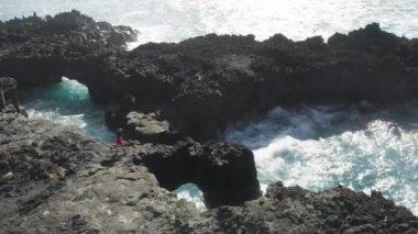 Lav kayasının tepesinde yürüyen bir turistin hava görüntüleri.