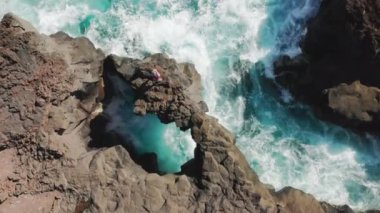 İnsan, tepeden bakıldığı gibi kayanın kenarında durur.