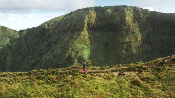 Человек, идущий по дороге в зеленых горах, остров Сао Фалуэль, Азорские острова, Португалия — стоковое видео