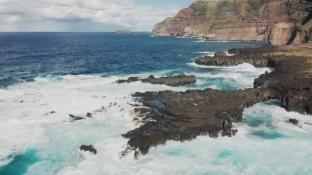 Légi kilátás a hatalmas habos hullámok fröccsenő ellen meredek partvonal. — Stock videók