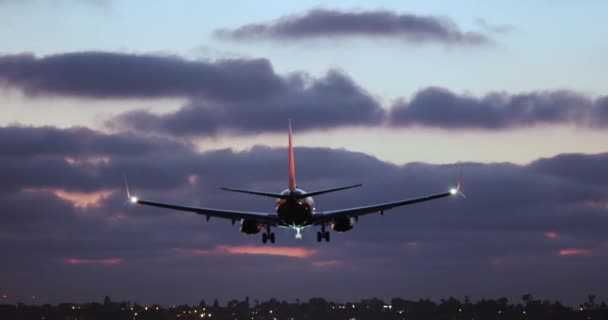 Κινηματογραφική πίσω όψη της προσγείωσης αεροπλάνο με μωβ σύννεφα στο παρασκήνιο, ΗΠΑ 4K — Αρχείο Βίντεο