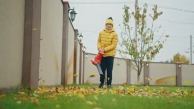 Genç çocuk sarı yaprakları üflüyor doğrudan kameraya, yavaş çekim çocukluğu