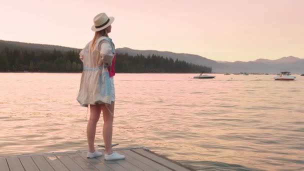 Mulher câmera lenta desfrutando do pôr do sol no lago Tahoe com luz cênica rosa do pôr do sol 4K — Vídeo de Stock