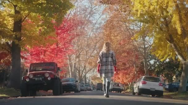 Stagione autunnale cinematografica 4K. Indietro vista donna godendo a piedi da piccola città in autunno — Video Stock