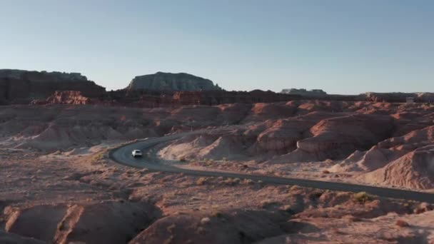 Drone volgende voertuig met toeristen reizen beroemde Goblin Valley bij zonsopgang — Stockvideo