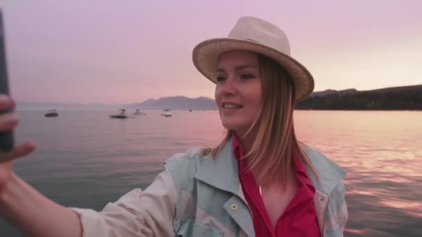 Porträtt av lycklig kvinna att göra selfie bild på smartphone kamera, rosa solnedgång — Stockvideo