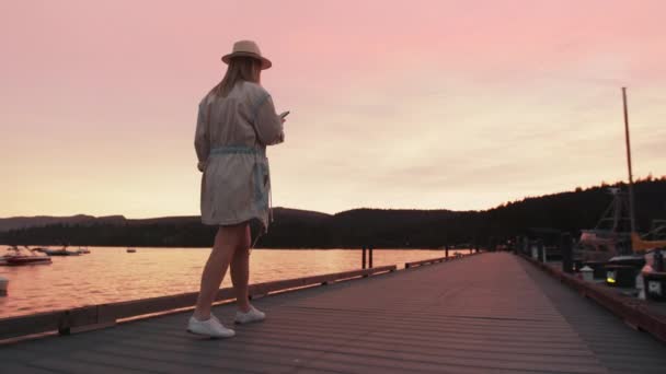 Mujer de cámara lenta mirando el teléfono con puesta de sol rosa cinematográfica sobre el lago Tahoe 4K — Vídeos de Stock