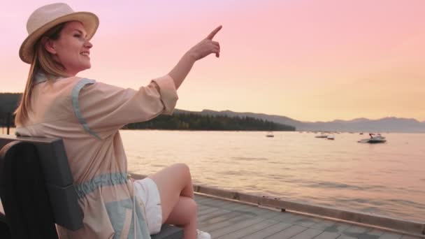 Relaxado sorrindo mulher apontando no pôr do sol rosa cênica sobre fundo lago Tahoe — Vídeo de Stock