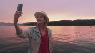 Modern teknoloji yaşam tarzı, Tahoe Gölü 'nde cep telefonu kullanan kadın, günbatımı 4K