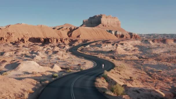 Luchtfoto filmische kronkelende weg loopt tussen rode steile bergen, rennende vrouw — Stockvideo