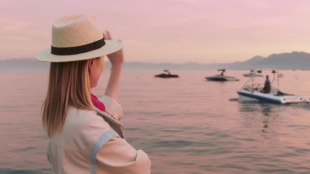 Ağır çekim kadın, Tahoe Gölü 'nde yelken açan insanları karşılıyor. Pembe günbatımı 4K. — Stok video