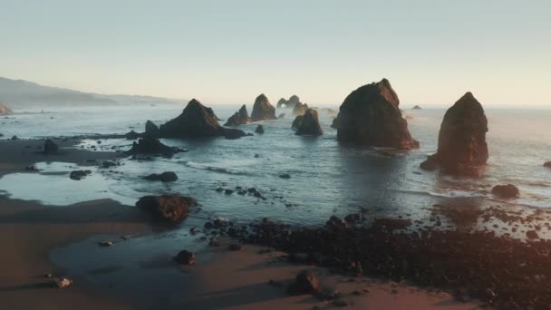 Vuelo de drones por encima de la playa de arena hasta el océano azul profundo entre rocas altas en el agua — Vídeos de Stock