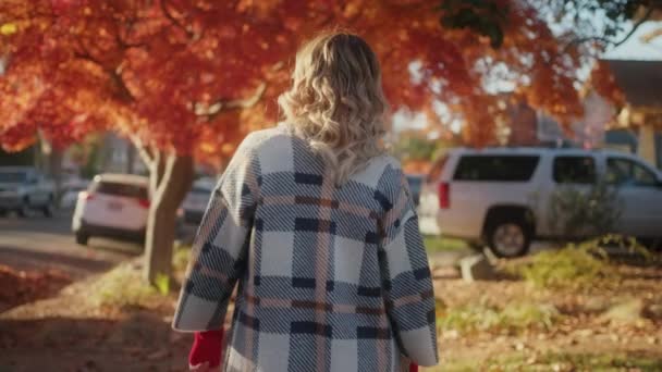 Vue arrière de la femme se déplace à travers le quartier d'automne en manteau chaud à la mode — Video