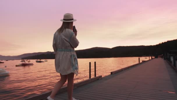 Viajero femenino con teléfono celular en la mano, mujer de cámara lenta puesta de sol sobre el lago Tahoe — Vídeos de Stock