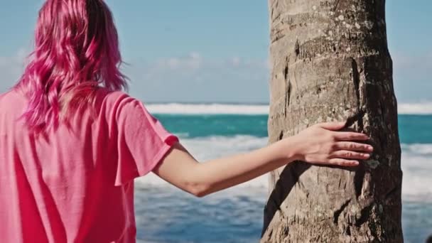 Hipster girl with trendy pink hair palming palm tree bark on Hawaii island beach — Stock Video
