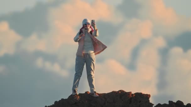 Mujer feliz usando teléfono inteligente, en línea en la cima de la montaña puesta del sol nubes de fondo — Vídeos de Stock