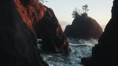 İnsansız hava aracı, gün batımında kayalık deniz kayalıklarından oluşan dar bir koridora yakın uçuyor.