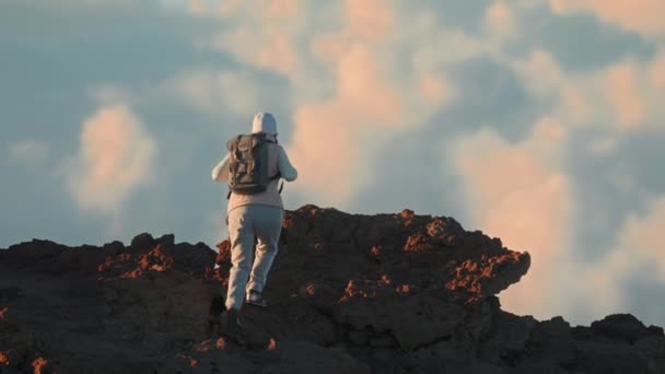 Escalada turística de roca volcánica de montaña en el paisaje nuboso escénico al atardecer cinematográfico — Vídeos de Stock