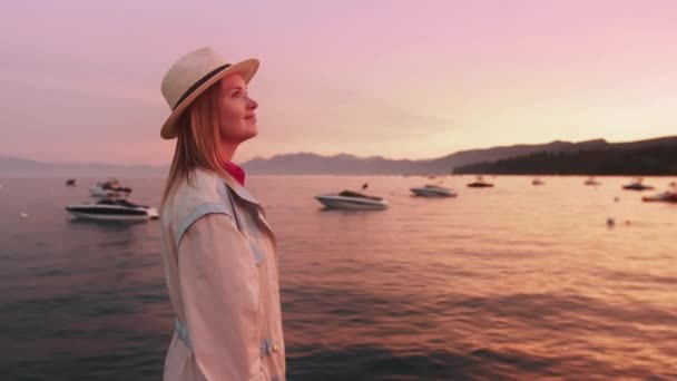 Mulher viajante elegante andando ao lado do lago, belo pôr do sol de ouro rosa em Tahoe — Vídeo de Stock