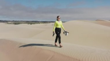 Neon fütüristik kostümlü güzel bir kadın ve kum tepeciklerinde yürüyen sanal gerçeklik gözlüğü.