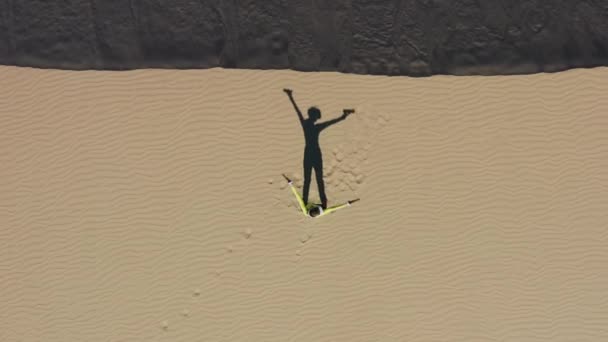 Excited young gamer girl staying on sand dune in desert, playing shooting game — Stock Video